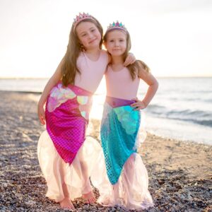 Twee meisjes aan het strand. Ze hebben beide een zeemeermin rokje aan. Het is een roos en blauw zeemeermin rokje. Ze dragen beide een zeemeermin tiara. De zeemeerminnenstaarten zijn onderaan mooi afgewerkt met tule.